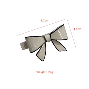Detailed view of cream acetate bow hair clip with black edges showing 8.7cm dimensions