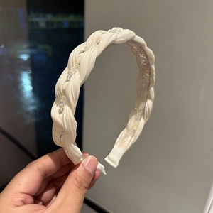 Close-up of cream woven headband featuring delicate clear beads and inner teeth for grip