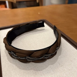 Nahaufnahme von braunem geflochtenem Stirnband mit edlem Strassbesatz und Satin-Finish