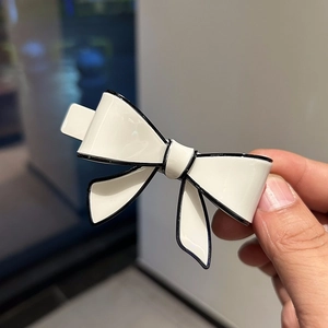 Detailed macro view of an ivory acetate bow hair clip with elegant black contrast edges
