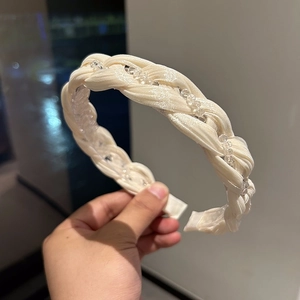 Close-up of cream braided crystal headband with elegant satin texture and bead detail