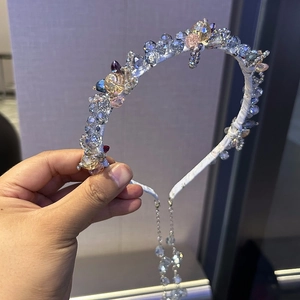 Détail d'un serre-tête en cristal avec perles multicolores et glands sur satin blanc