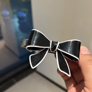 Detail shot of black and white acetate bow hair clip with polished finish and metal spring