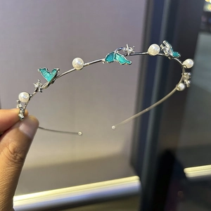 Détail du serre-tête avec perles blanches, oiseaux en émail bleu sarcelle et strass brillants