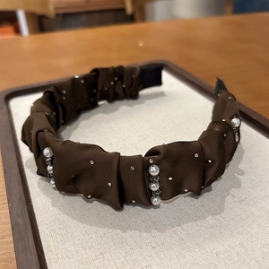 Macro detail of brown satin pleated headband with white pearls and sparkling rhinestones