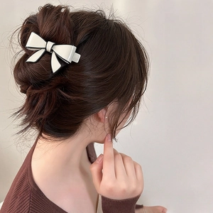 Rear view of a minimalist white acetate bow hair clip with black edges in hair