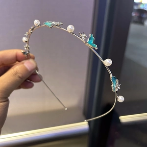 Détail d'un serre-tête en métal argenté avec perles, strass et papillons bleus