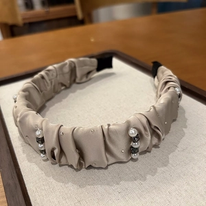 Detail of champagne pleated satin headband with scattered pearls and rhinestones