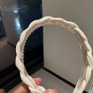 Detail showing the non-slip inner comb teeth and cream white twisted fabric of the headband