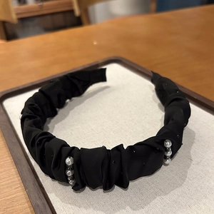 Detailed macro view of black pleated headband with white pearls and sparkling black rhinestones