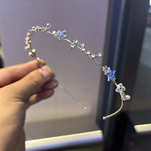 Détail d'un serre-tête argenté fin avec des étoiles pailletées bleues et cristaux