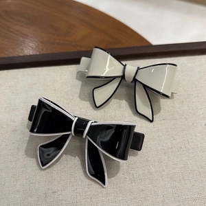 Close-up of acetic acid bow hair clips in black and beige with contrasting borders
