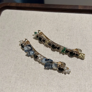 Detailed macro view of crystal beaded hair clips in navy blue and emerald green finishes