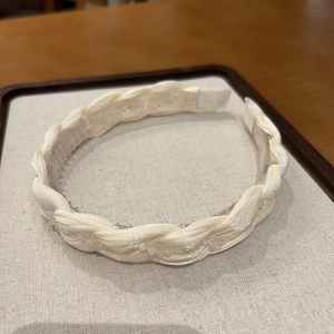 Close-up of a woven cream headband featuring elegant crystal accents and inner grip teeth