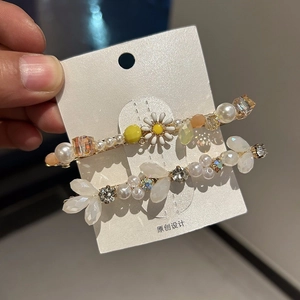 Elegant crystal hair clips set with pearls and daisies on a white display card