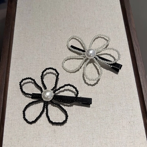 Détail de barrettes à fleurs avec perles centrales et clips en ruban gros-grain