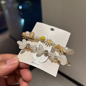 Detailed shot of handmade hair clips featuring daisies, white pearls, and floral beads