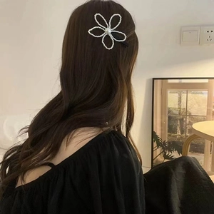 Barrette à fleurs en perles blanches de style français sur de longs cheveux bouclés