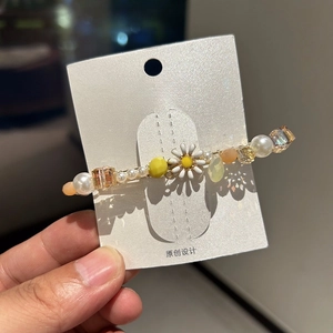Detail of handmade duckbill clip with white pearls and yellow daisy floral crystal beads