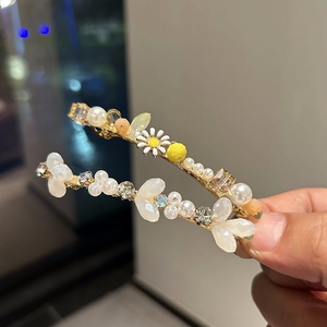 Detailed view of handmade hair clips featuring daisies, pearls, and sparkling crystals