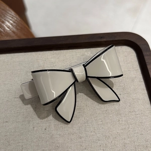 Detail of elegant acetate bow hair clip with black contrast trim on a display tray
