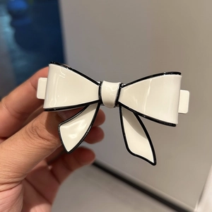 Elegant white acetate bow hair clip with black border detailing for a chic hairstyle