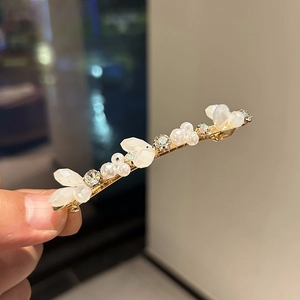 Detail of luxury hair clip with crystals, pearls and petals on gold metal base
