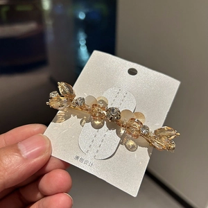 Detail of a handmade golden spring hair clip with sparkling crystals and beads