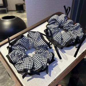 Detailed view of two black and white checkered bow scrunchies with white pearl accents