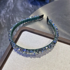 Detailed close-up of dark green crystal headband with intricate beadwork and luxury texture