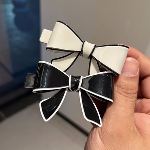 Close-up of black and white acetate bow hair clips with refined contrast edging detail