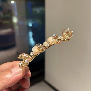Detail of a vintage gold hair clip featuring amber crystals and frosted pink beads