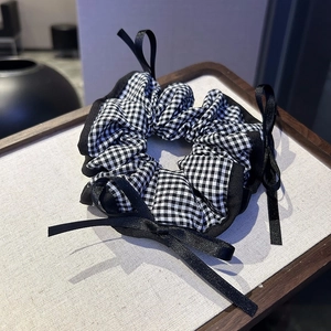 Close-up of black and white gingham scrunchie with elegant black satin ribbon bow