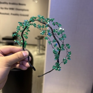 Detail of handmade green crystal beads woven with black metal wire on a bridal headband