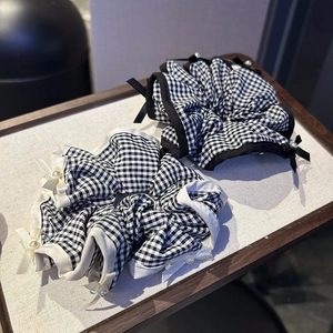 Gingham scrunchies set with black and white bow details and pearls in a wooden tray