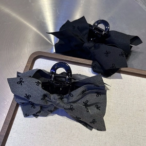 Detail of elegant bow hair claw clips in black and floral patterns on metal surface