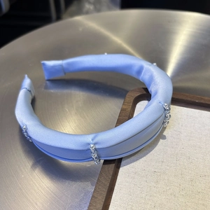 Detail of light blue satin headband with white pearl and transparent bead accents