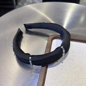 Detail of black satin headband featuring white pearls and grey beads on a wood frame