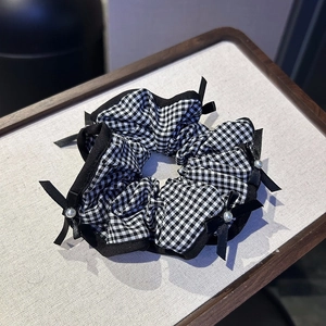Close-up of black and white checkered scrunchie with ribbon bows and faux pearl details