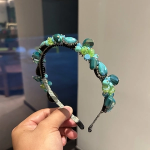 Close-up of luxury emerald and teal crystal hand-beaded headband with sparkling rhinestones