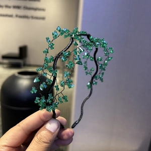 Detailed view of handmade beaded headband featuring green crystals on a black wire frame