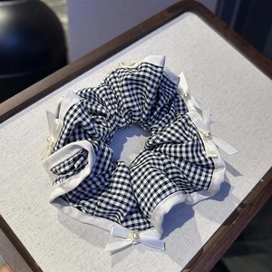 Black and white plaid scrunchie with ribbons and pearls shown on a wooden tray