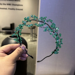 Macro detail of emerald crystal beads on a delicate woven bridal headband accessory