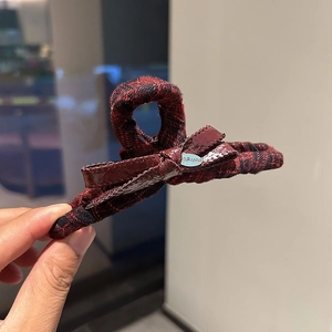 Detail of red and black plaid fabric hair claw clip with a glossy bow and metal plate