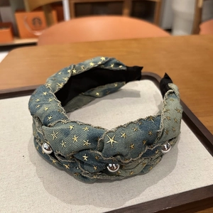 Detailed close-up of blue denim braided headband with gold star embroidery and silver beads