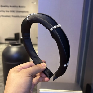 Detailed macro view of black satin padded headband featuring pearl and crystal beads