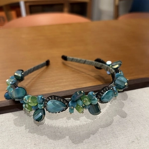 Detailed macro view of handmade peacock green crystal beads on a stylish headband