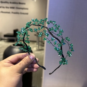 Close-up of handmade green crystal beads woven on a dark metal mesh headband