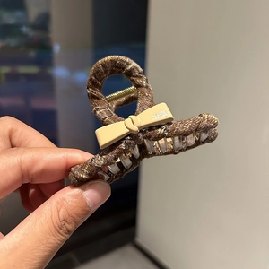 Elegant brown tweed hair claw clip with a chic cream bow for autumn and winter styles