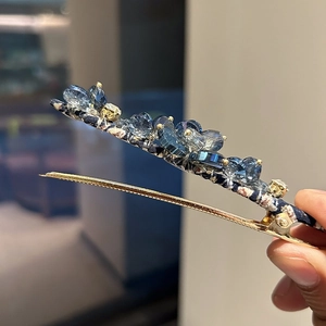 Elegant gold metal hair clip with blue crystals and floral fabric detail for women